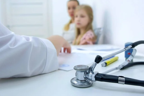 Madre hija en recepción en pediatra, médico toma notas, primer plano de la mano . — Foto de Stock