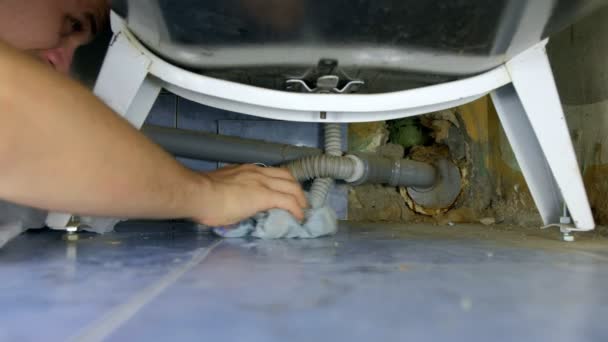 Hydraulik naprawia rury wodne pod wanną w łazience odpinając rurę i odprowadzając wodę. — Wideo stockowe