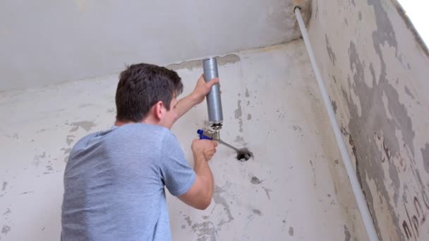 L'uomo riempie il buco nel muro di schiuma di montaggio lastra di cemento rendendo le riparazioni a casa . — Video Stock