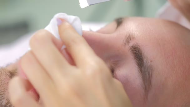 Cosmetologue fait une procédure de nettoyage du visage par ultrasons pour le jeune homme à la clinique. — Video
