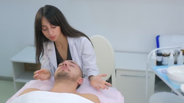 Hombre joven en consulta por cosmetóloga mujer en clínica de belleza . — Vídeo de stock