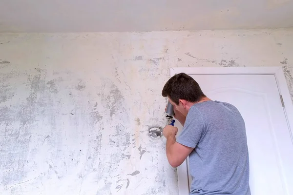 Mann stopft Loch in Wand aus Betonplatte und montiert Schaum für Reparaturen zu Hause. — Stockfoto