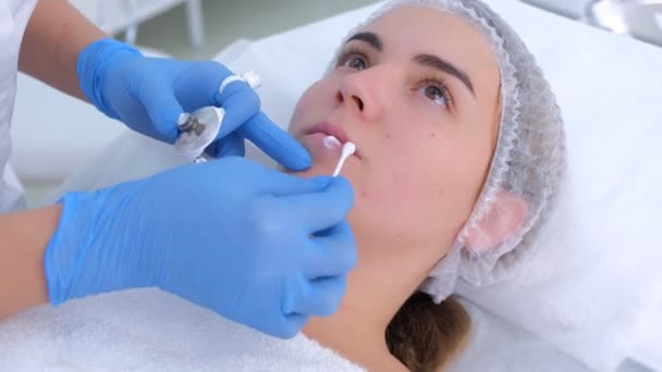 Beautician applying cream with anesthetic on woman lips before permanent makeup. — Stock Video