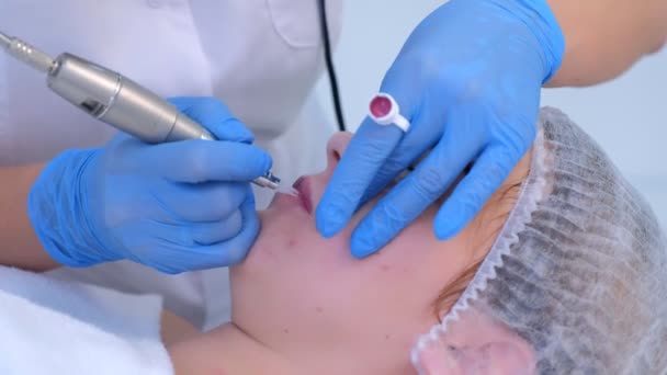 Cosmetologue faire des lèvres procédure de microblading pour fille en utilisant une machine à tatouer. — Video