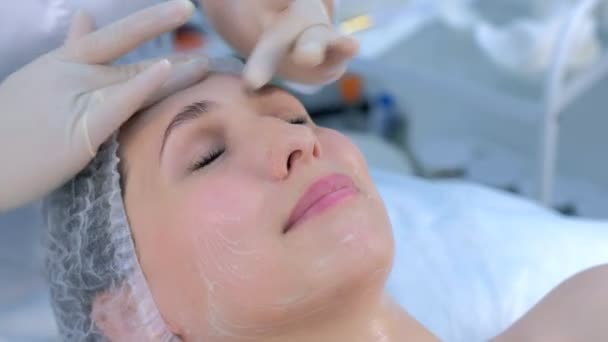 Kozmetik uzmanı kadın yüzünde nemlendirici kremle yüz masajı yapıyor.. — Stok video