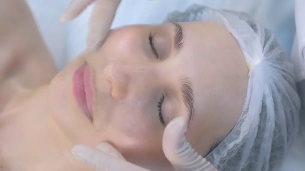 Schoonheidsspecialiste maken van gezicht en massage op volwassen vrouwen gezicht in schoonheidskliniek. — Stockvideo
