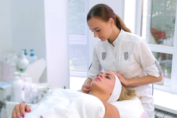 Cosmetoloog voorbereiding klant naar cosmetische schoonheid procedure zetten hoofdband. — Stockfoto