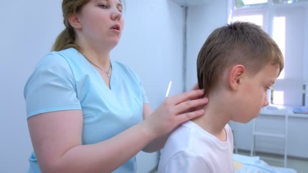 Doctor professional massagist makes therapy head massage to teen boy in clinic. — Stock Video