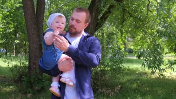 Молодой папа держит дочку гуляя в городском парке, семейный портрет . — стоковое видео