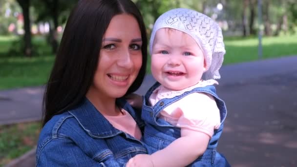 Genç anne kucağında bebek kızıyla kameraya bakıyor ve gülümsüyor.. — Stok video