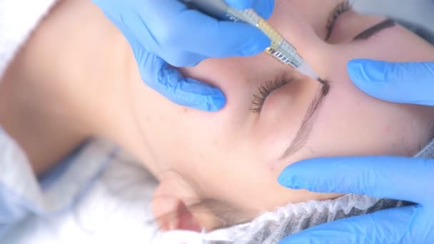 Beautician making eyebrows microblading procedure in beauty salon for woman. — Stock Video