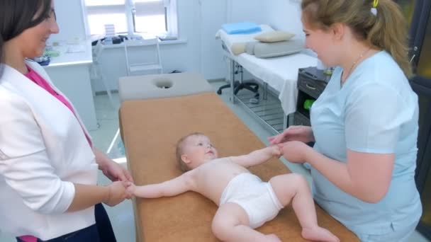 Профессиональный массажист делает массаж ребенку, лежащему на диване в клинике . — стоковое видео