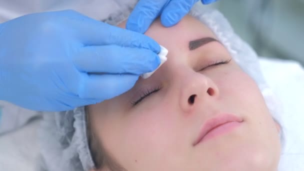 Beautician is wiping eyebrows using cotton pads making eyebrows microblading. — Stock Video