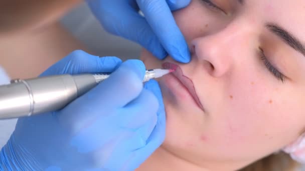 Esteticista aplicando maquillaje permanente en los labios usando máquina de tatuaje, vista de primer plano. — Vídeos de Stock