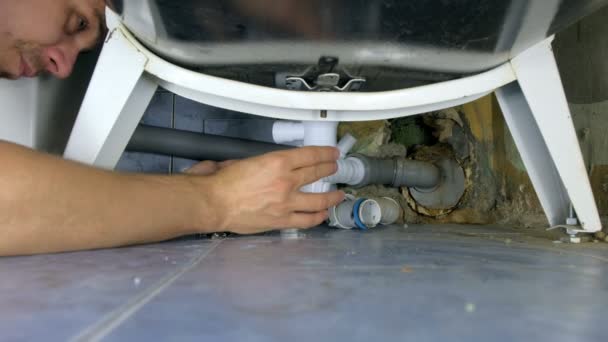 Plumber repairs replacement of pipes with new ones under bath in bathroom. — Stock Video