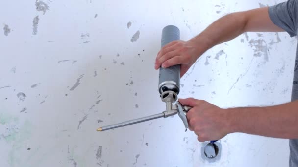 Man construction worker screws a bottle of mounting foam to tool, hands closeup. — 비디오