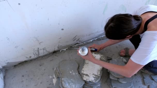 Werkster vrouw vult scheur tussen muur en cement vloer met montage schuim. — Stockvideo