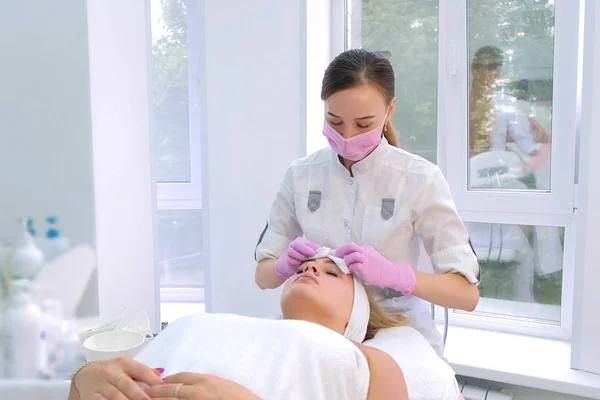 Schoonheidsspecialiste wast gezicht van vrouwen klant voor te bereiden op cosmetische procedure. — Stockfoto