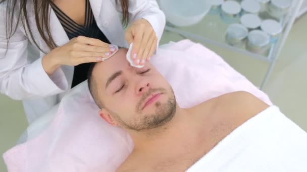 Man op schoonmaken gezicht procedure door vrouw cosmetoloog in schoonheidskliniek. — Stockvideo