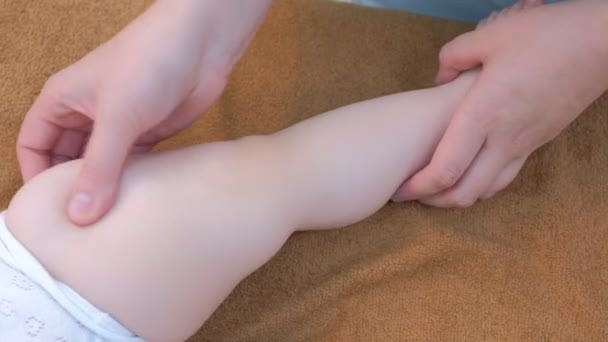 Professionele arts massagist het maken van massage aan baby op been in kliniek, closeup. — Stockvideo