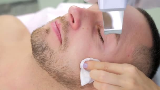 Cosmetologue fait une procédure de nettoyage du visage par ultrasons pour le jeune homme à la clinique. — Video