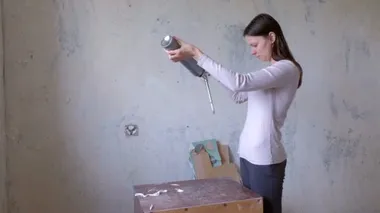 Kadın köpük malzemesi monte etmeye çalışıyor, odada tadilat yapıyor..