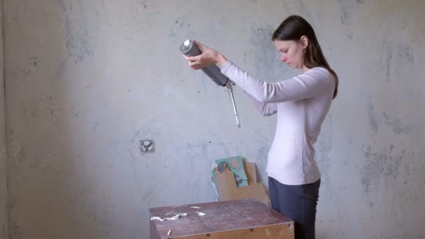 Mujer tratando de cómo montar equipo de espuma de trabajo, renovación en la habitación . — Vídeo de stock