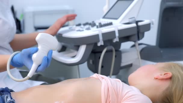 Врач делает УЗИ брюшной полости для девочки с помощью сканера, вид сбоку. — стоковое видео