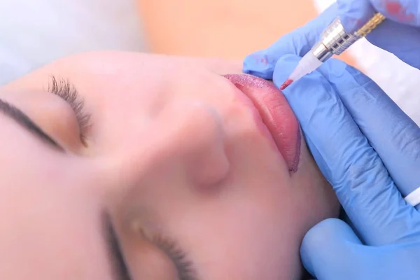 Cosmetologist making lips microblading procedure for girl using tattoo machine. — Stock Photo, Image