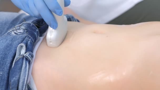 Врач делает УЗИ брюшной полости для девочки с помощью сканера, вид крупным планом. — стоковое видео