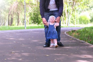 Bebek şehir parkında babasının elini tutarak ilk adımı atmaya çalışıyor..