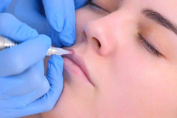 Esteticista aplicando maquiagem permanente nos lábios usando máquina de tatuagem, vista de close-up. — Fotografia de Stock