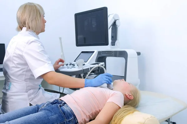 Doctor examining patient child girl thyroid gland using ultrasound scanner.