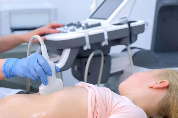 Doctor is making abdominal ultrasound for child girl using scanner, side view. — Stock Photo, Image