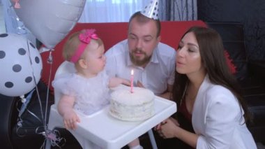 Aile portresi anne, baba ilk doğum gününde pastaya mum üflüyor..