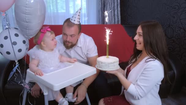 Mutter schenkt Tochter eine Torte mit Kerze auf Geburtstagsfeier eines einjährigen Mädchens. — Stockvideo