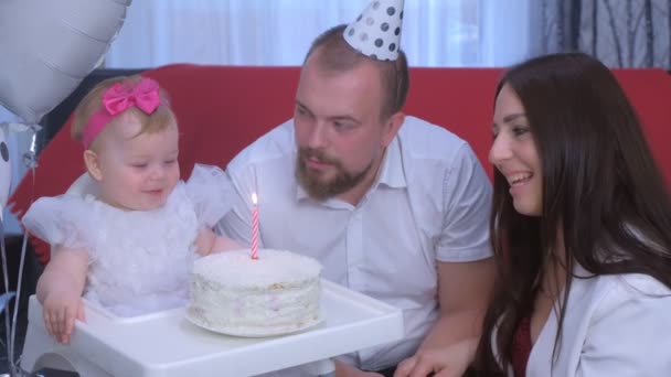 Familie portret moeder, vader en baby meisje op eerste verjaardag met taart en kaars. — Stockvideo