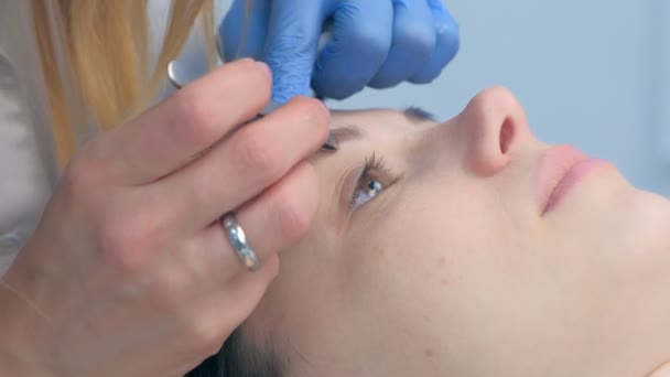Косметолог вириває брови пінцетом жінці в салоні краси, крупним планом . — стокове відео