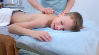Doktor masajcı, klinikte omurgası olan genç bir çocuğa terapi masajı yapıyor..