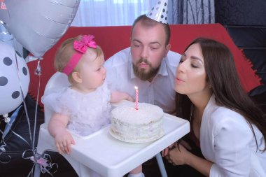 Aile portresi anne, baba ilk doğum gününde pastaya mum üflüyor..