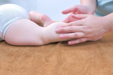 Profesyonel doktor masörü klinikte bacağındaki bebeğe masaj yapıyor..