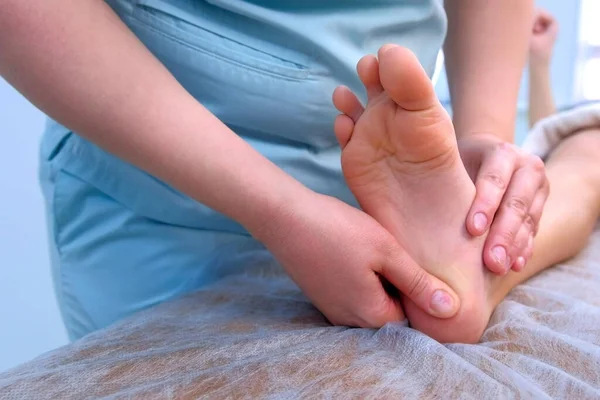 Médico massagista fazendo massagem terapêutica para menino a pé na clínica, close-up . — Fotografia de Stock