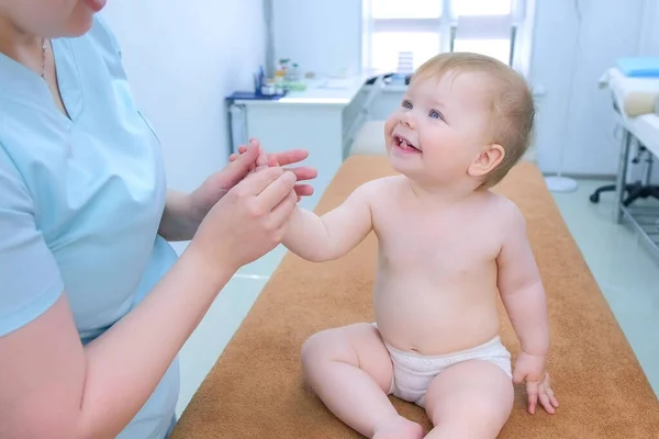 Profesional médico masajista haciendo masaje al bebé sonriente en la mano en la clínica . — Foto de Stock