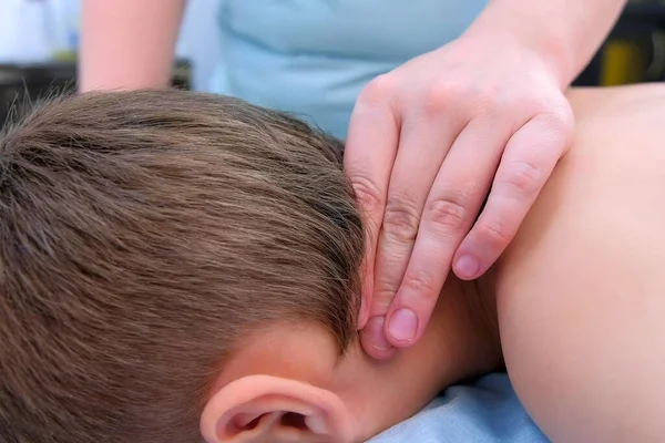 Médico massagista fazendo massagem terapêutica para adolescente menino no pescoço na clínica . — Fotografia de Stock