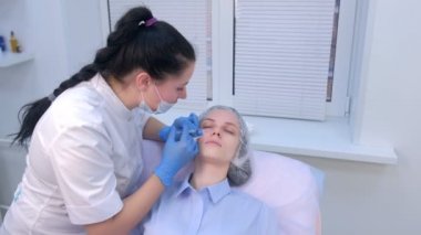 Kozmetik uzmanı kadın cildine birden fazla enjeksiyon yapıyor..