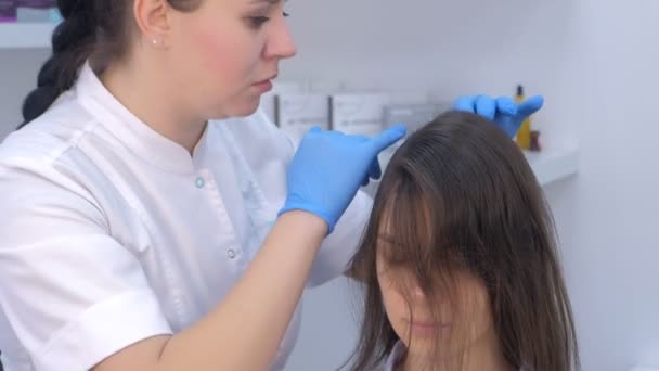 医師トリコロジストは診療所で女性患者の髪を診察. — ストック動画