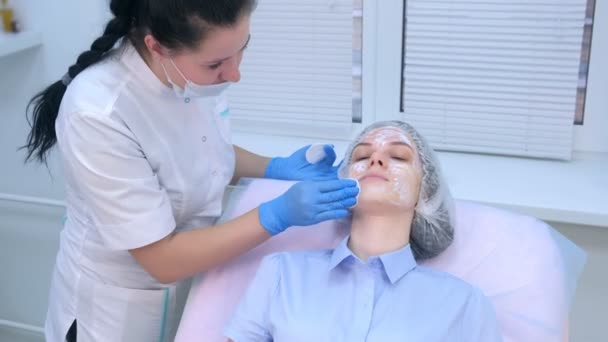 Cosmetoloog veegt crème met verdoving van het gezicht voor biorevitalisatie. — Stockvideo