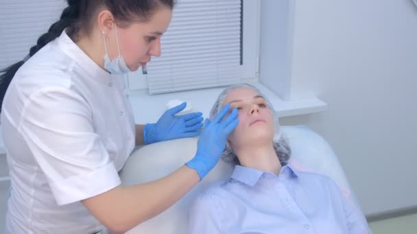 Косметолог наносит лечебный крем после инъекций биоревитализации на лицо. — стоковое видео