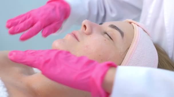 Gezichtsmassage voor jonge vrouw door arts cosmetoloog in kliniek, closeup view. — Stockvideo
