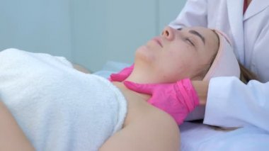 Klinikteki doktor kozmetik uzmanı tarafından genç bir kadın için boyun ve yüz masajı.